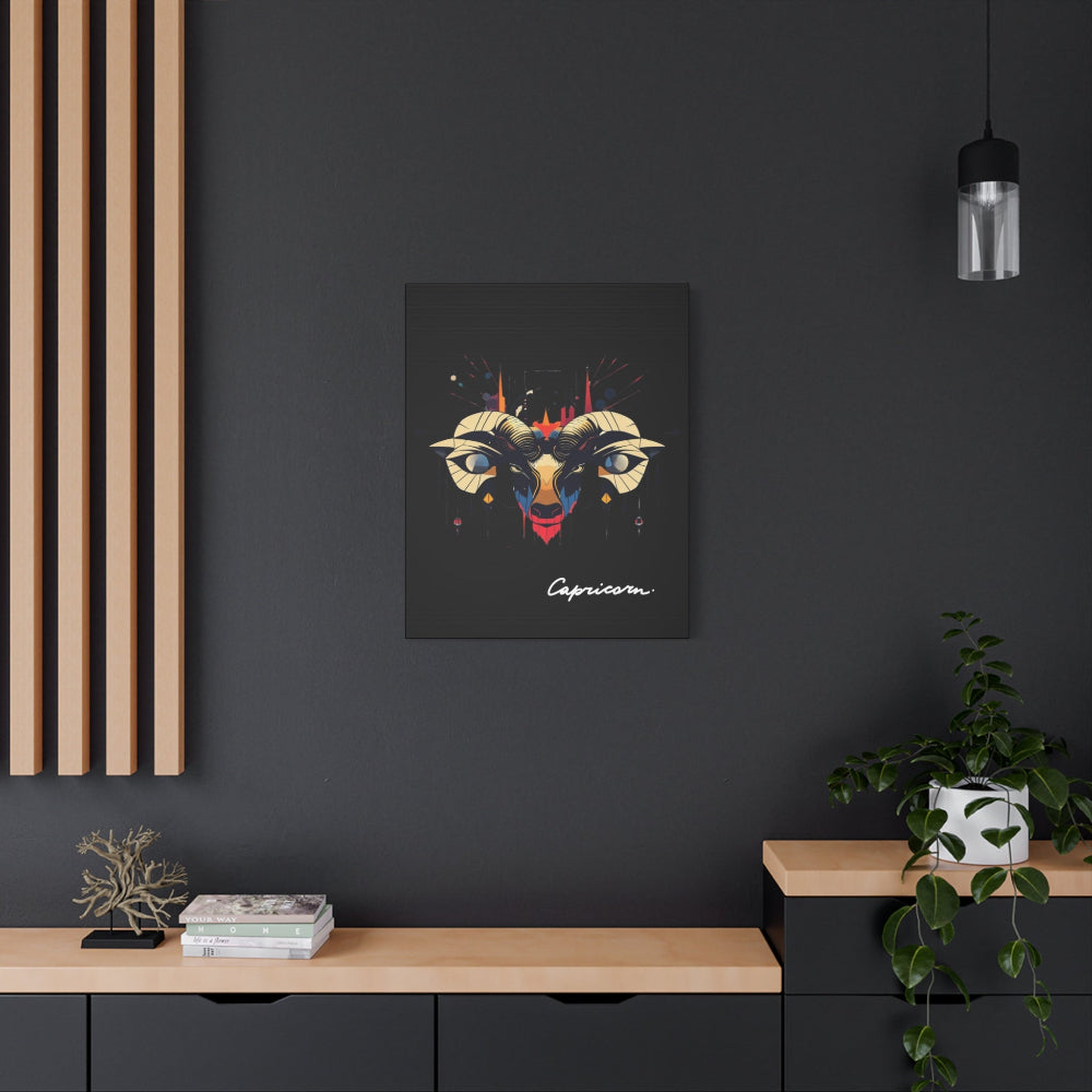 Black canvas wall art print of colorful abstract Capricorn goat head with large curved horns, intense eyes, geometric patterns, and cosmic splatters on dark background, featuring "Capricorn" in elegant white cursive hung on a dark grey wall above a wooden shelf with potted plants.