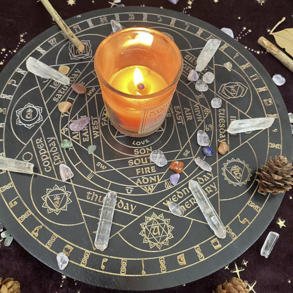 Lit orange candle placed in the center of a black and gold Wheel of the Year divination board, surrounded by clear quartz points, tumbled crystals, pinecones, and a wooden wand. Mystical pagan altar setup for seasonal rituals and spiritual practice.