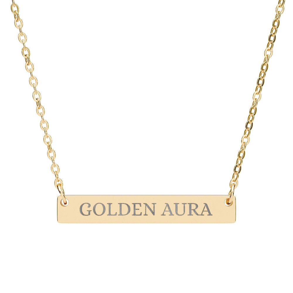 Gold bar necklace with engraved uppercase text "GOLDEN AURA" on a sleek matte pendant, suspended on a delicate matching gold chain. Minimalist motivational affirmation jewelry for radiance, positivity, and energetic glow.