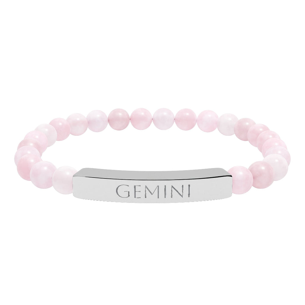 Bracelet with polished rose quartz beads in soft pink tones, natural translucent glow, paired with a silver curved bar engraved "GEMINI" in uppercase letters. Stretch-fit zodiac-inspired crystal jewelry.