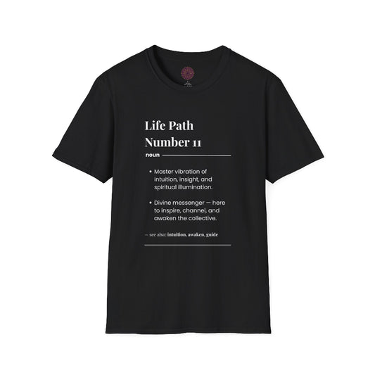 Black unisex cotton t-shirt laid out flat featuring bold Life Path Number 11 numerology print in dictionary style: exact text reading "Life Path Number 11 noun · Master vibration of intuition, insight, and spiritual illumination. · Divine messenger — here to inspire, channel, and awaken the collective. – see also: intuition, awaken, guide". Motivational spiritual numerology crewneck tee flat lay with visible purple/gold zodiac wheel inner tag.