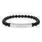 Bracelet with polished black onyx beads and silver curved bar engraved "VIRGO" in uppercase letters. Stretch-fit zodiac-inspired crystal jewelry.