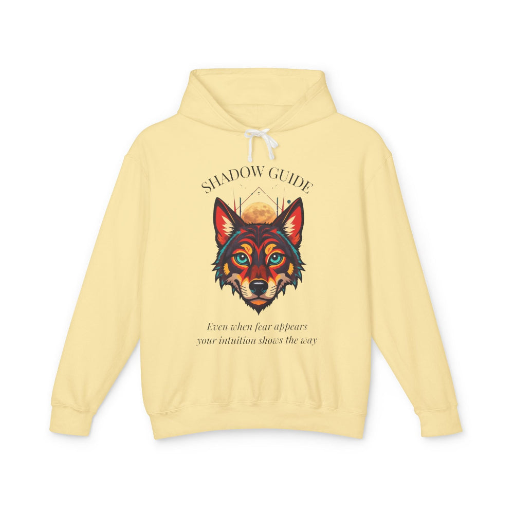 Pale yellow "Shadow Guide" graphic hoodie featuring fierce wolf portrait in colorful splash-art style, moon element, inspirational text about intuition guiding through fear