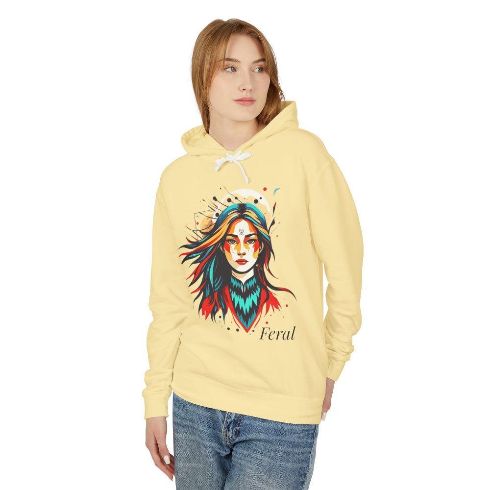 Young woman modeling yellow hoodie with vibrant artistic portrait of a fierce woman with long multicolored flowing hair, teal and red face paint, colorful splash design, third-eye motif, "Feral" text below