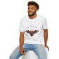 White unisex cotton t-shirt modeled by smiling man with curly hair and beard, featuring bold "Trust the Silence" graphic: vibrant abstract owl with detailed feathers, intense expression, colorful geometric accents, and dynamic paint splatters in red, orange, teal, blue, and gold tones around an orange moon. Arched white text "TRUST THE SILENCE" above and smaller quote "Even when the world is quiet, wisdom speaks softly" below. Motivational spiritual empowerment crewneck tee.