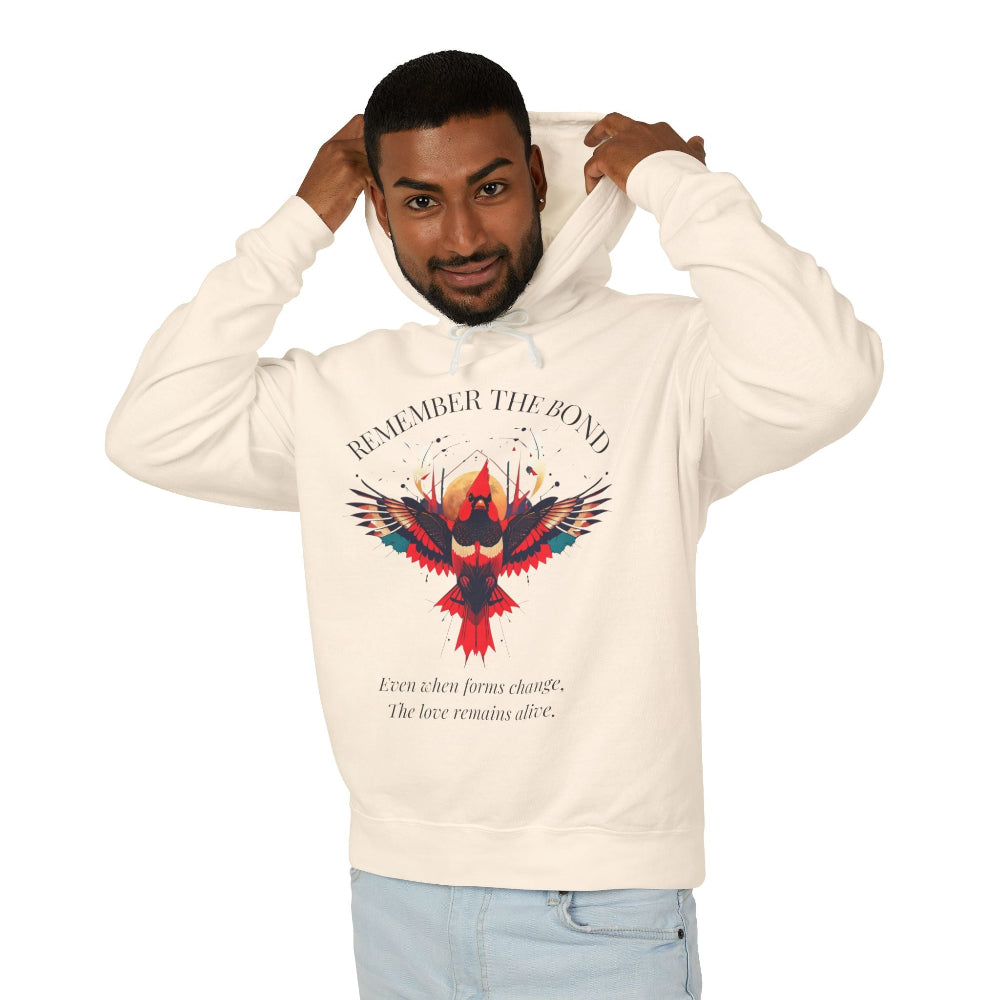 Man modeling a cream hoodie with 'Remember The Bond' inspirational bird graphic and quote 'Even when forms change, The love remains alive' printed on the front.