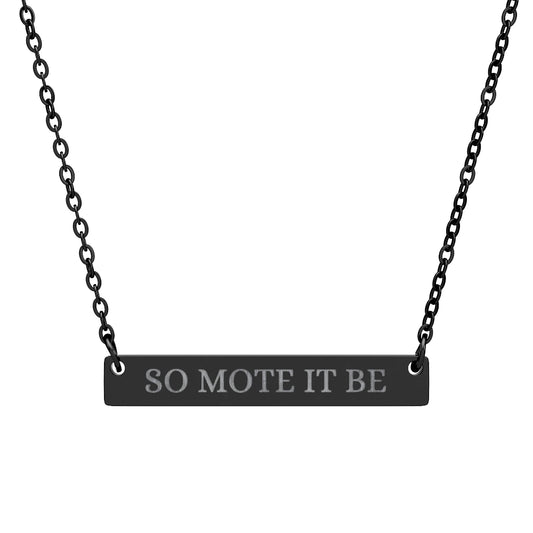 Black bar necklace featuring engraved silver text "SO MOTE IT BE" on a matte black pendant, suspended on a delicate black chain. Minimalist occult-inspired jewelry with Wiccan/Pagan affirmation for manifestation and intention setting.