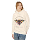 Woman wearing an off-white hoodie featuring a vibrant bee graphic with the text "SACRED ALIGNMENT" above and the quote "Even when progress is quiet, the harvest is still forming" below. Casual streetwear style with blue jeans.