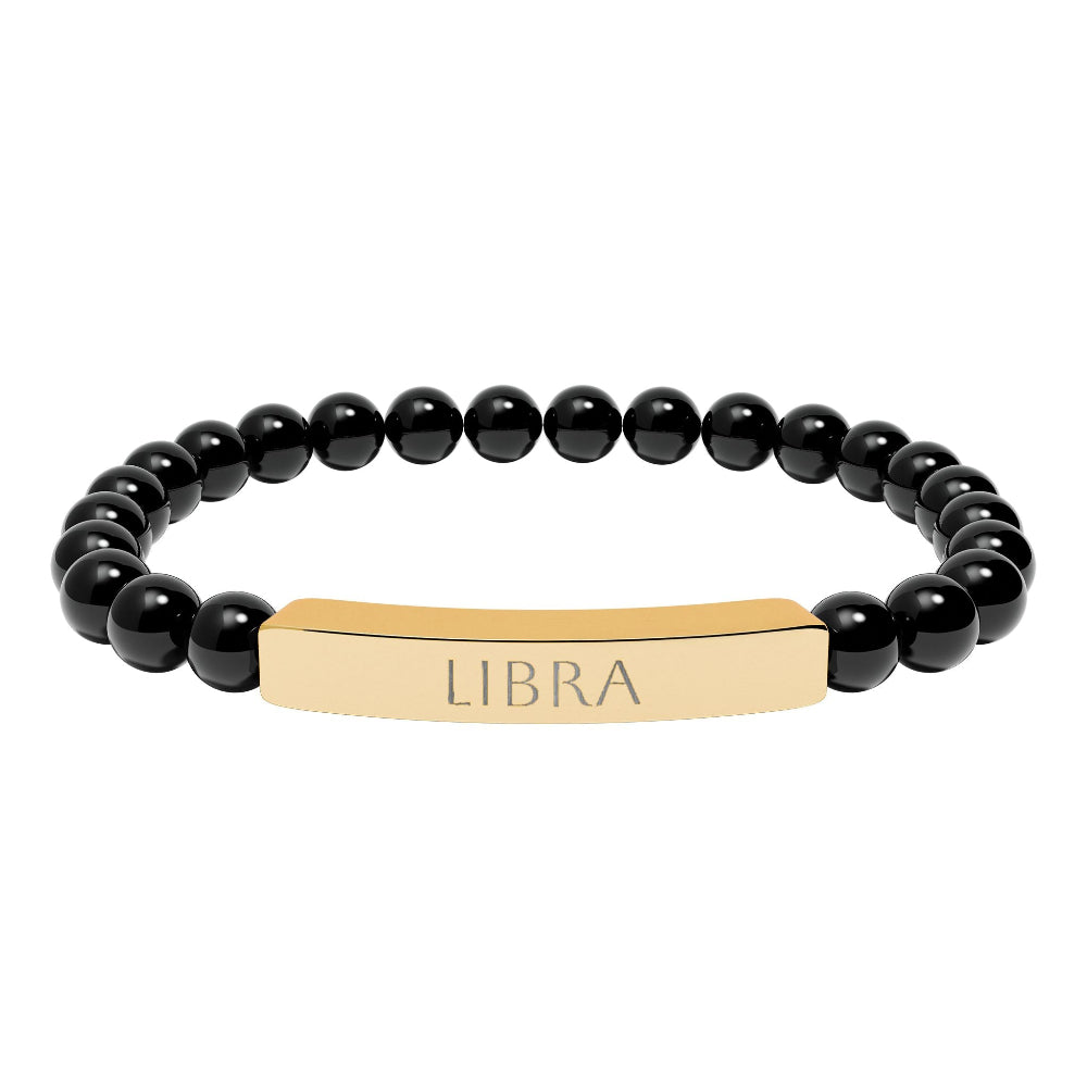 Bracelet with polished black onyx beads and gold-plated curved bar engraved "LIBRA" in uppercase letters. Stretch-fit zodiac-inspired crystal jewelry.