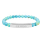 Bracelet with polished turquoise beads in soft aqua-blue tones with natural veining and speckles, featuring a silver curved bar engraved "GEMINI" in uppercase letters. Stretch-fit zodiac-inspired crystal jewelry.