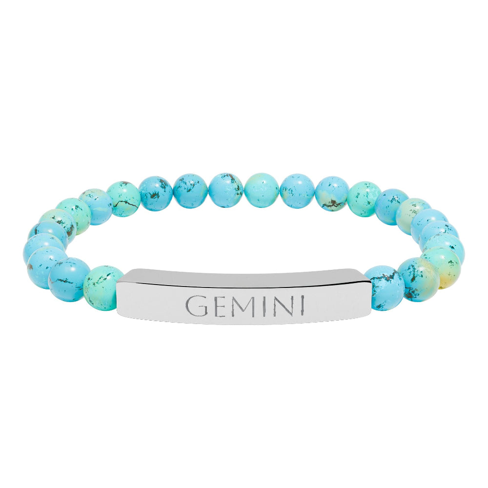 Bracelet with polished turquoise beads in soft aqua-blue tones with natural veining and speckles, featuring a silver curved bar engraved "GEMINI" in uppercase letters. Stretch-fit zodiac-inspired crystal jewelry.