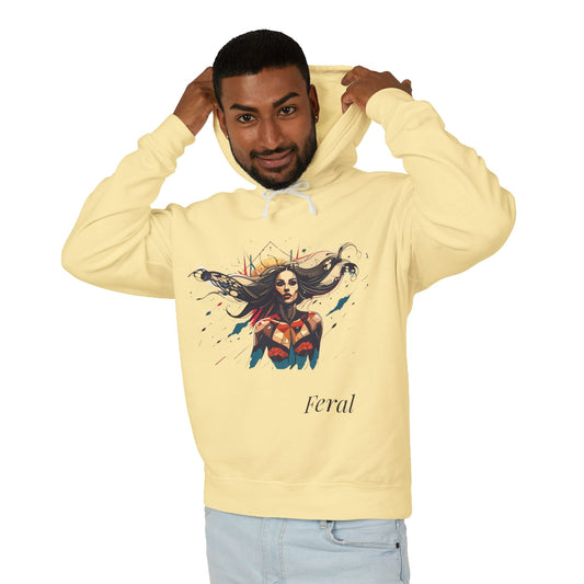 Young man with short hair pulling up the hood of a yellow hoodie featuring vibrant artistic print of a fierce woman with long flowing hair, red-orange armored top, colorful paint splash design, "Feral" text below