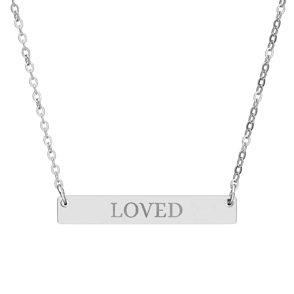 Silver bar necklace with engraved uppercase text "LOVED" on a sleek matte silver pendant, suspended on a delicate matching silver chain. Minimalist motivational affirmation jewelry for self-love, worthiness, and emotional healing.