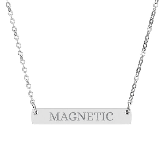 Silver bar necklace with engraved uppercase text "MAGNETIC" on a sleek matte silver pendant, suspended on a delicate matching silver chain. Minimalist motivational affirmation jewelry for attraction, charisma, and positive energy.