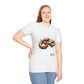 White unisex cotton t-shirt modeled by smiling plus-size female with long blonde hair, hand on hip, featuring bold Year of the Snake graphic: vibrant abstract coiled snake in infinity/figure-8 shape with fierce expression, detailed scales, hypnotic eyes, and dynamic multicolored paint splatters in gold, red, black, green, teal, and orange tones exploding outward. Chinese text "蛇年" (Year of the Snake) printed below in black. Zodiac Chinese New Year motivational crewneck tee.