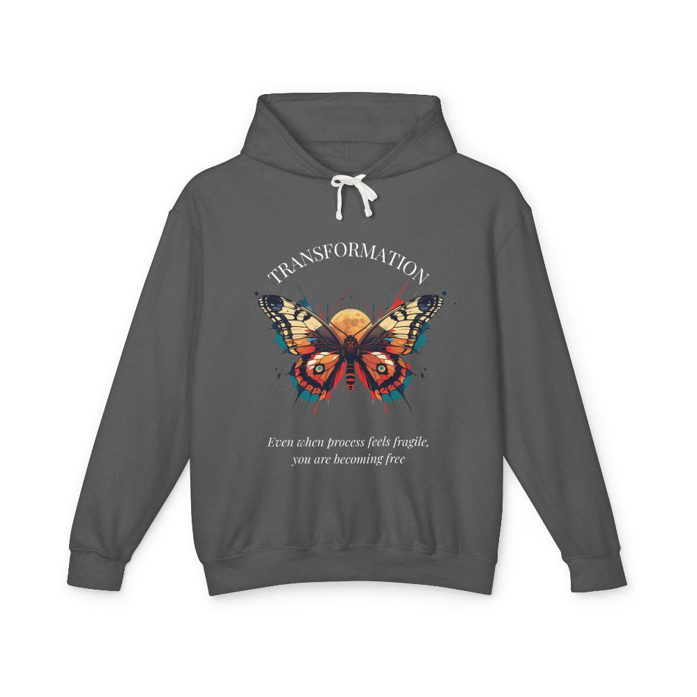 Charcoal gray hoodie featuring colorful abstract butterfly graphic with moon background, "TRANSFORMATION" arched above, and quote "Even when process feels fragile, you are becoming free