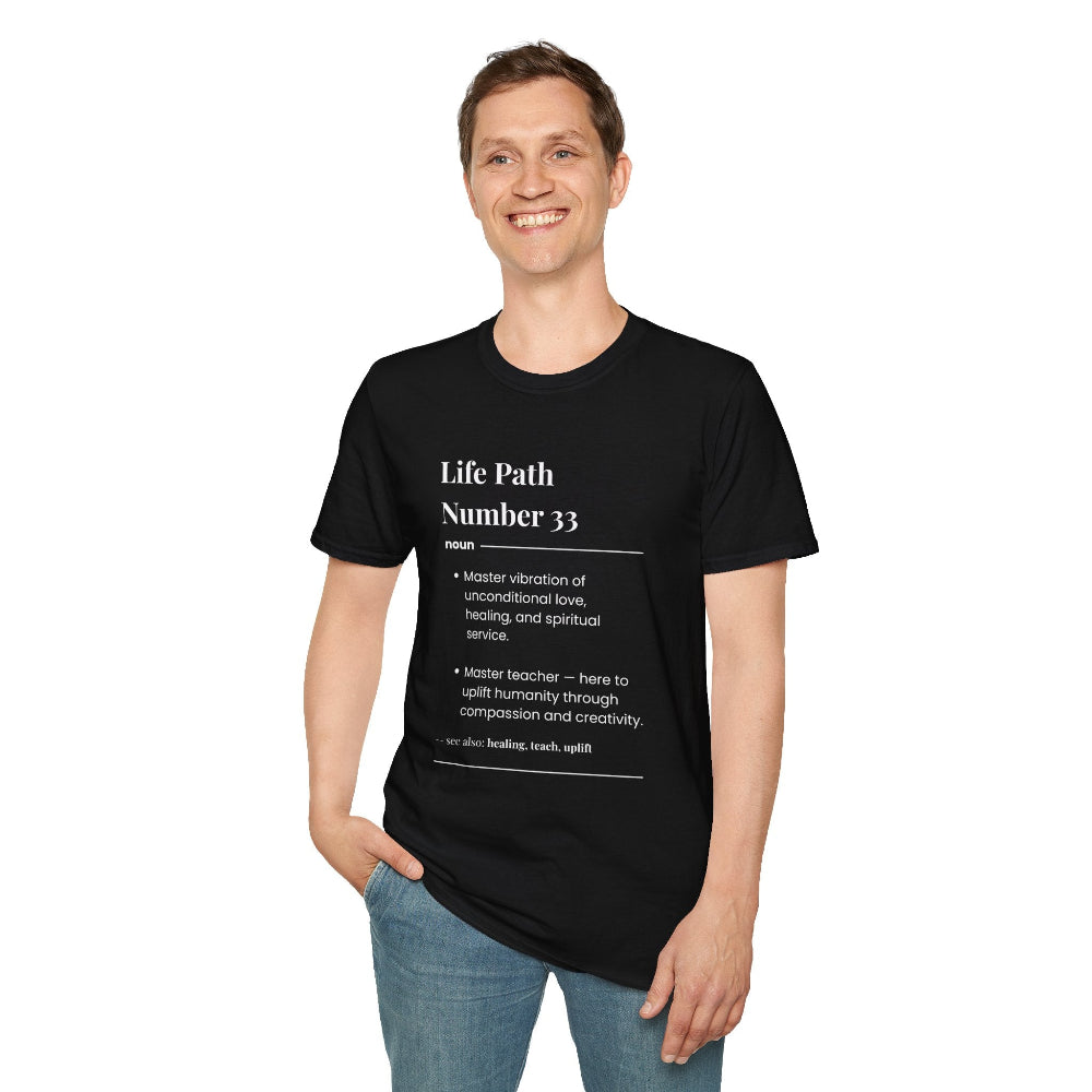 Black unisex cotton t-shirt modeled by smiling man with short brown hair, featuring bold Life Path Number 33 numerology print in dictionary style: exact text reading "Life Path Number 33 noun · Master vibration of unconditional love, healing, and spiritual service. · Master teacher — here to uplift humanity through compassion and creativity. – see also: healing, teach, uplift". Motivational spiritual numerology crewneck tee.