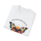 White folded unisex cotton t-shirt featuring bold "Transformation" graphic print: vibrant abstract butterfly with detailed wings, intense expression, colorful geometric accents, and dynamic paint splatters in red, orange, teal, blue, and gold tones bursting outward around an orange moon background. Arched white text "TRANSFORMATION" above. Motivational spiritual empowerment crewneck tee flat lay.