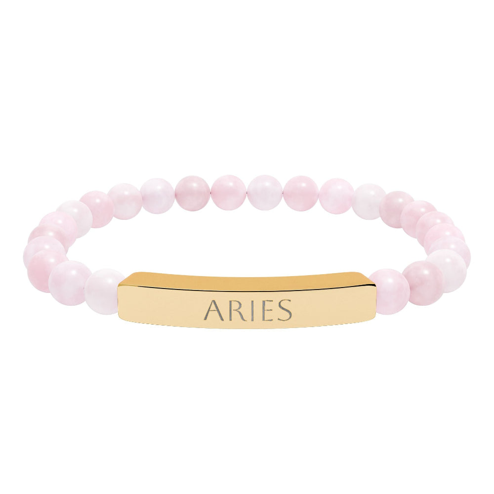 Bracelet with polished rose quartz beads in soft pink tones, natural translucent glow, paired with a gold-plated curved bar engraved "ARIES" in uppercase letters. Stretch-fit zodiac-inspired crystal jewelry for passion, courage, and leadership.