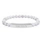 Bracelet with polished white howlite beads featuring natural gray-black veining and marbling, paired with a silver curved bar engraved "TAURUS" in uppercase letters. Stretch-fit zodiac-inspired crystal jewelry.