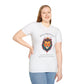 White plus-size unisex cotton t-shirt modeled by smiling woman with long blonde hair, hand on hip, featuring bold "Bold Presence" graphic: vibrant abstract lion head portrait with intense expression, colorful geometric accents, and dynamic paint splatters in red, orange, teal, blue, and gold around an orange moon. Arched white text "BOLD PRESENCE" above and smaller quote "Even when challenges arise, your heart leads with confidence" below. Motivational spiritual empowerment crewneck tee.