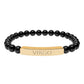 Bracelet with polished black onyx beads and gold-plated curved bar engraved "VIRGO" in uppercase letters. Stretch-fit zodiac-inspired crystal jewelry.