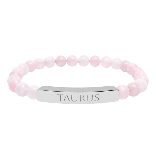 Bracelet with polished rose quartz beads in soft pink tones, natural translucent glow, paired with a silver curved bar engraved "TAURUS" in uppercase letters. Stretch-fit zodiac-inspired crystal jewelry.