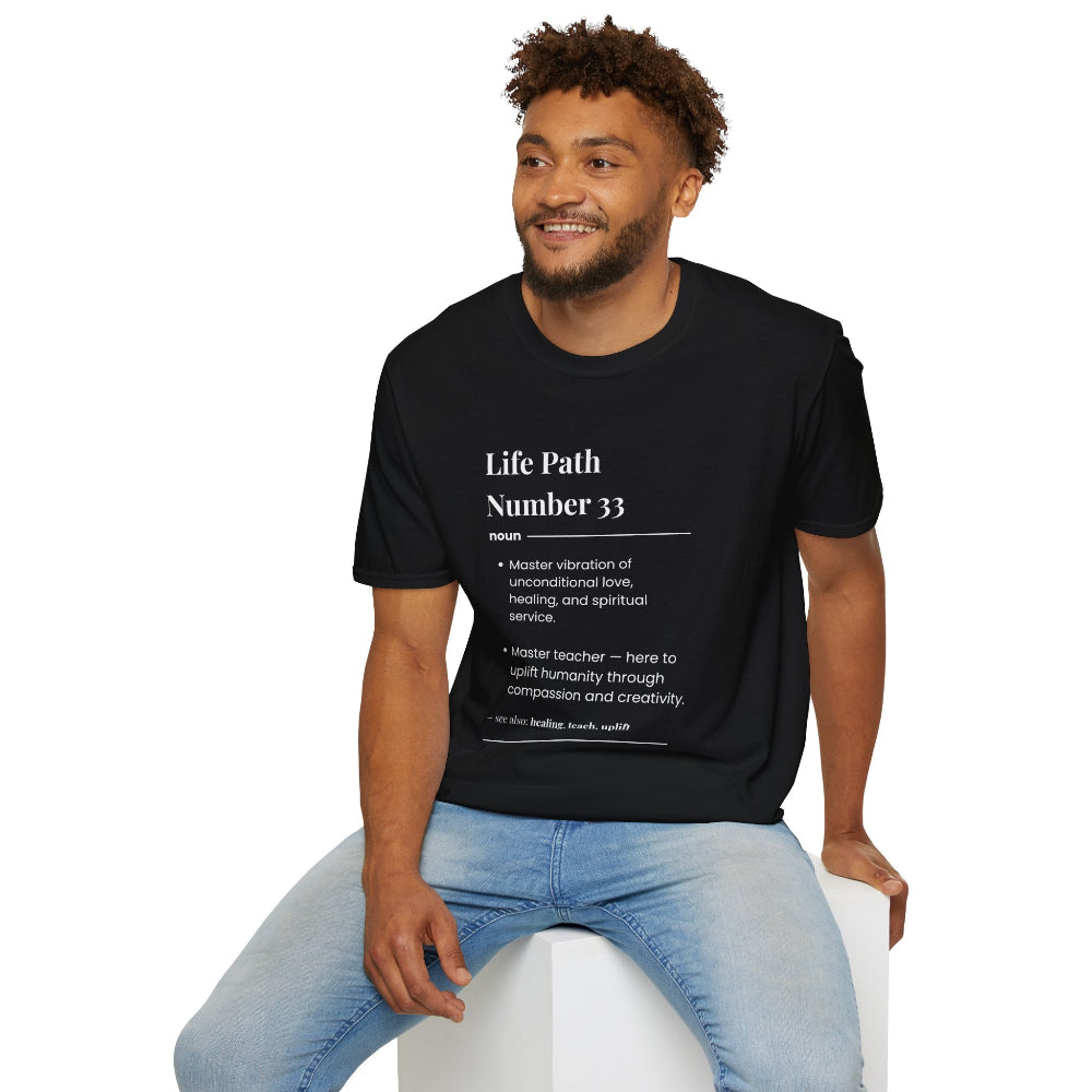 Black unisex cotton t-shirt modeled by smiling man with curly hair and beard, featuring bold Life Path Number 33 numerology print in dictionary style: exact text reading "Life Path Number 33 noun · Master vibration of unconditional love, healing, and spiritual service. · Master teacher — here to uplift humanity through compassion, kindness, and creativity. – see also: compassion, release, service". Motivational spiritual numerology crewneck tee.