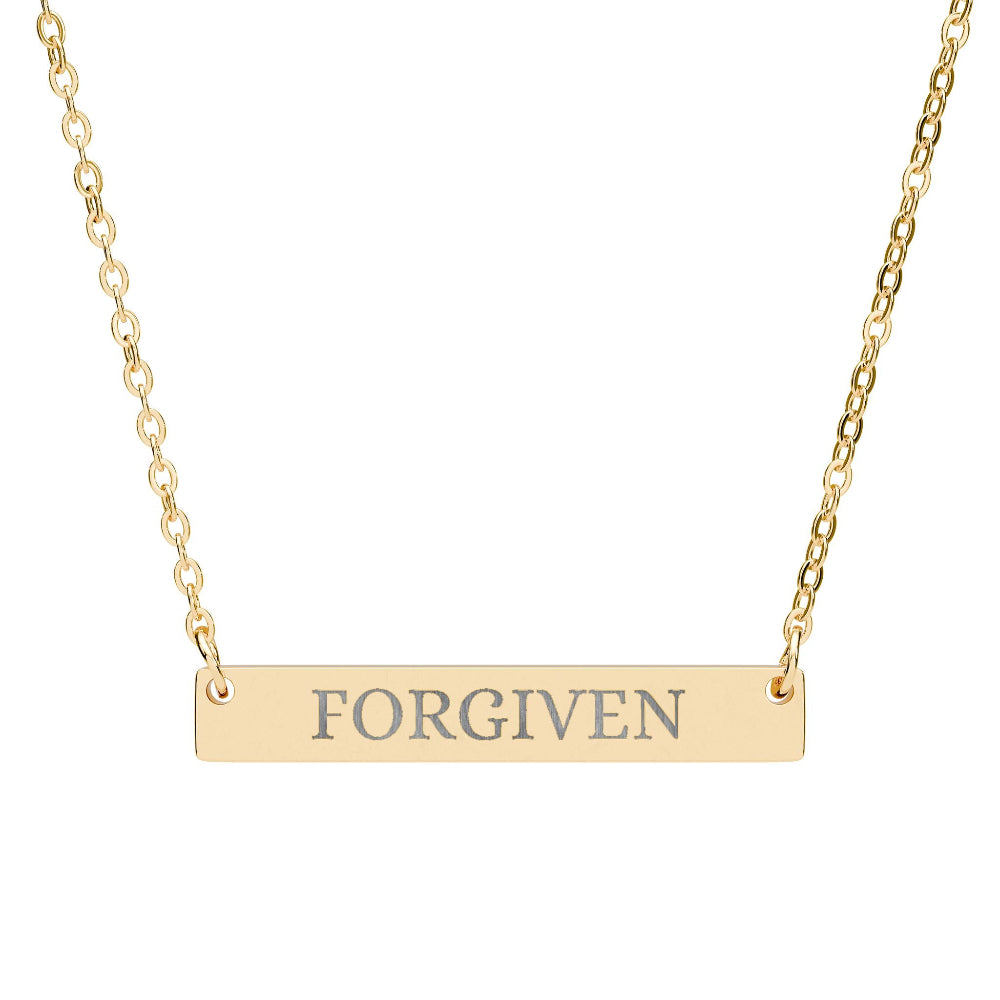 Gold bar necklace with engraved uppercase text "FORGIVEN" on a sleek matte pendant, suspended on a delicate matching gold chain. Minimalist motivational affirmation jewelry for forgiveness, healing, and emotional release.