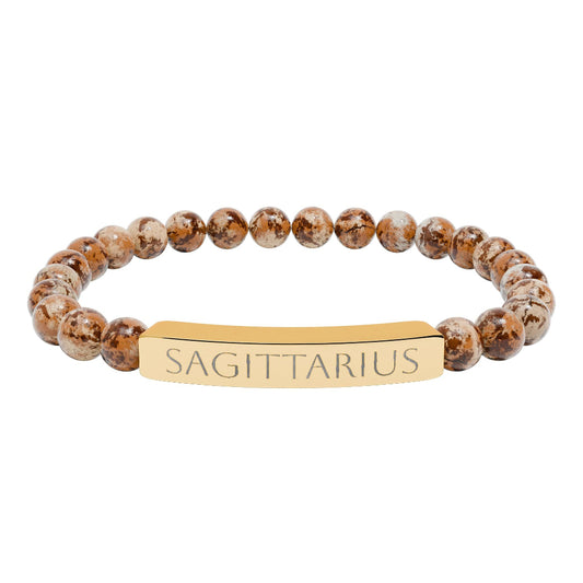 Bracelet with polished leopard jasper beads in earthy brown tones with natural veining, featuring a gold-plated curved bar engraved "SAGITTARIUS" in uppercase letters. Stretch-fit zodiac-inspired crystal jewelry.