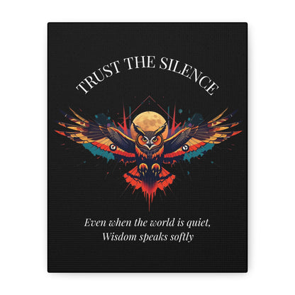 Close up of black canvas wall art print featuring colorful abstract owl with intense eyes, detailed feathers, geometric accents, and cosmic splatters on dark background. Arched white text "TRUST THE SILENCE" above and quote "Even when the world is quiet, wisdom speaks softly" below.