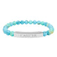 Bracelet with polished turquoise beads in soft aqua-blue tones with natural veining and speckles, featuring a silver curved bar engraved "CANCER" in uppercase letters. Stretch-fit zodiac-inspired crystal jewelry.