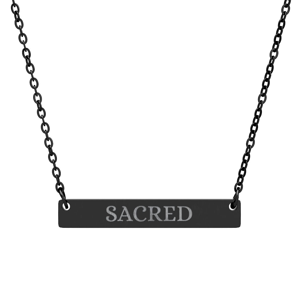Black bar necklace with engraved uppercase text "SACRED" on a matte black pendant, suspended on a delicate black chain. Minimalist spiritual affirmation jewelry for sacred energy and divine connection.16.1sFast