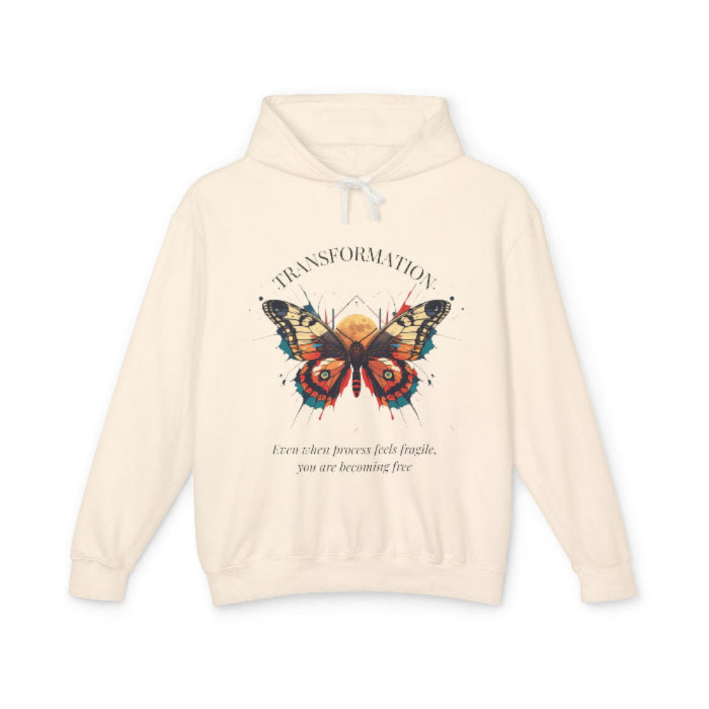 Cream hoodie featuring a colorful abstract butterfly graphic with the word "TRANSFORMATION" arched above and the quote "Even when process feels fragile, you are becoming free