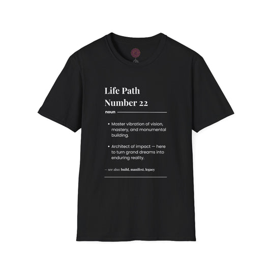 Black unisex cotton t-shirt laid out flat featuring bold Life Path Number 22 numerology print in dictionary style: exact text reading "Life Path Number 22 noun · Master vibration of vision, mastery, and monumental building. · Architect of impact — here to turn grand dreams into enduring reality. – see also: build, manifest, legacy". Motivational spiritual numerology crewneck tee flat lay with visible purple/gold zodiac wheel inner tag.