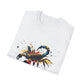 White folded unisex cotton t-shirt featuring bold Scorpio zodiac graphic print: vibrant abstract scorpion silhouette with raised stinger, intense glowing eyes, detailed tail and pincers, geometric patterns, and explosive multicolored paint splatters in gold, red, navy, teal, and black tones bursting outward. Elegant black cursive "Scorpio" text below. Astrology zodiac motivational crewneck tee.