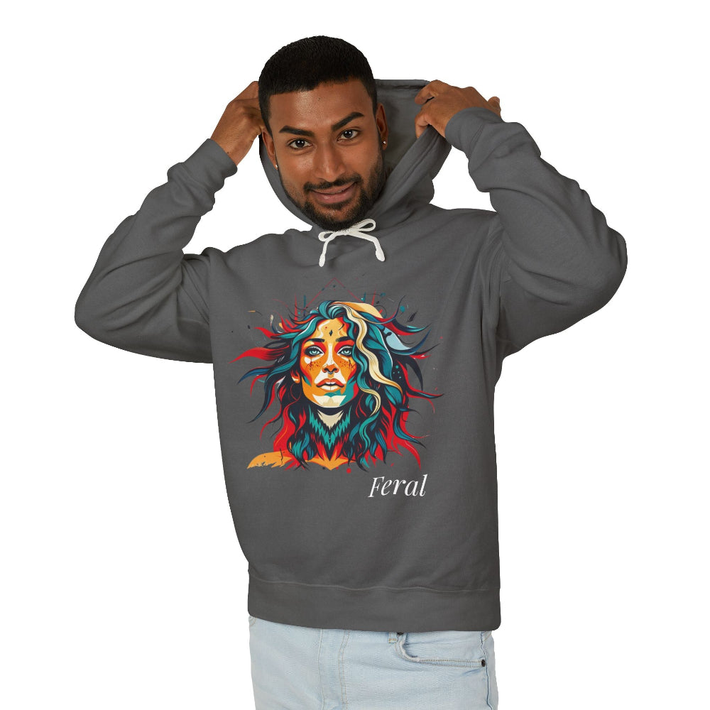 Young man with short hair pulling up the hood of a dark gray hoodie featuring vibrant artistic portrait of a fierce woman with curly multicolored flowing hair, teal red blue face accents, bold makeup, "Feral" text below