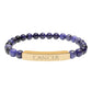Bracelet with polished lapis lazuli and black onyx beads in deep blue and black tones, featuring a gold-plated curved bar engraved "CANCER" in uppercase letters. Stretch-fit zodiac-inspired crystal jewelry.