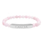 Bracelet with polished rose quartz beads in soft pink tones and natural translucent glow, paired with a silver curved bar engraved "CANCER" in uppercase letters. Stretch-fit zodiac-inspired crystal jewelry for emotional depth, nurturing, and intuition.