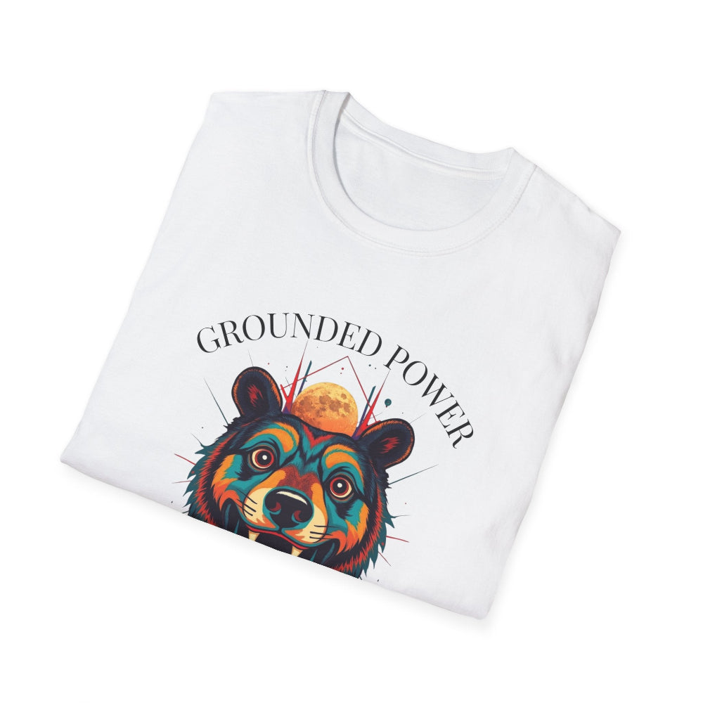 White folded unisex cotton t-shirt featuring bold "Grounded Power" graphic: vibrant abstract bear head portrait with intense expression, colorful geometric accents, and dynamic paint splatters in red, orange, teal, blue, and gold tones bursting outward around an orange moon background. Arched white text "GROUNDED POWER" above and smaller inspirational quote "Even when life is overwhelming, your roots keep you steady" below. Motivational spiritual empowerment crewneck tee.