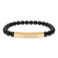 Bracelet with polished black onyx beads and gold-plated curved bar engraved "GEMINI" in uppercase letters. Stretch-fit zodiac-inspired crystal jewelry.