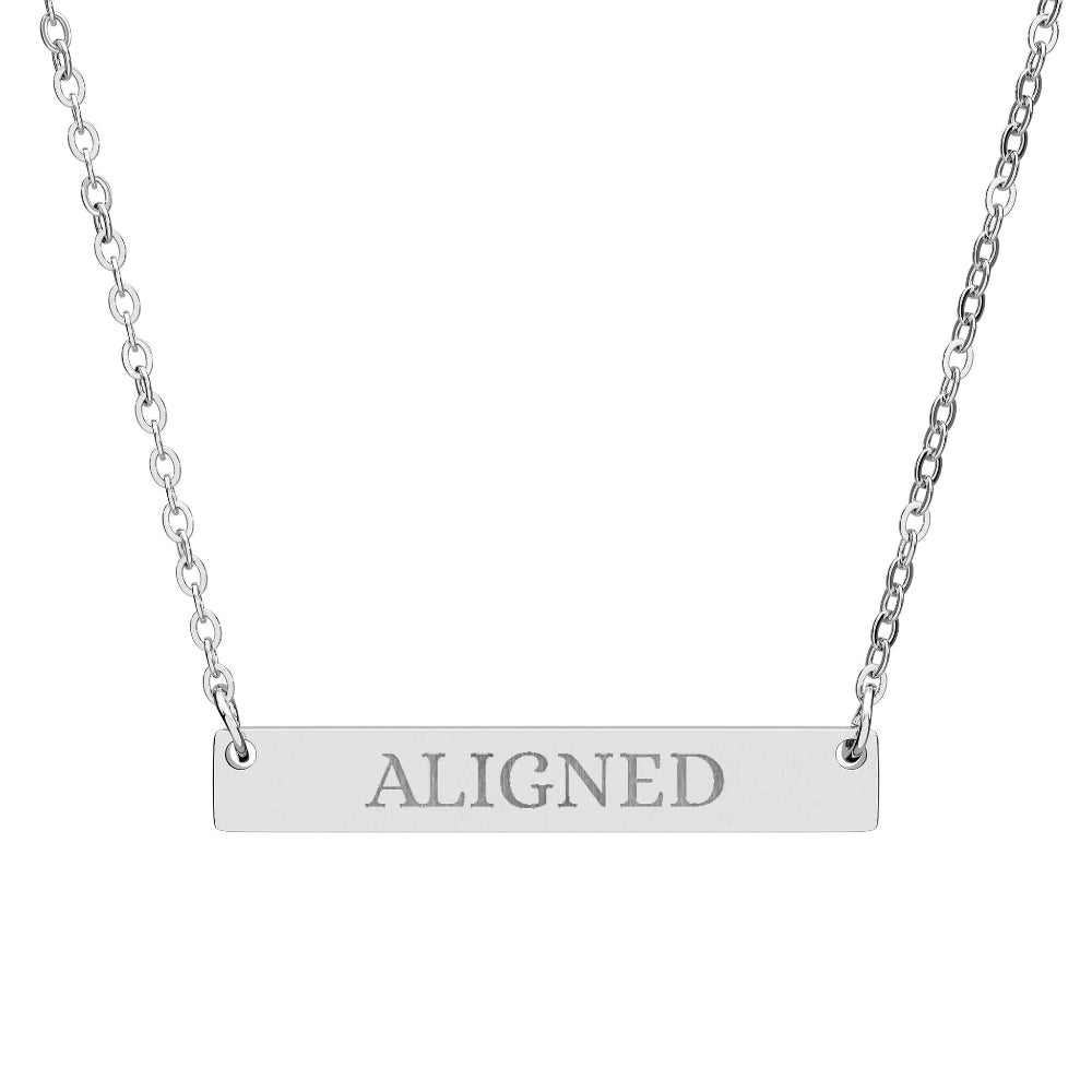 Silver bar necklace with engraved uppercase text "ALIGNED" on a sleek matte silver pendant, suspended on a delicate matching silver chain. Minimalist motivational affirmation jewelry for alignment, balance, and spiritual harmony.