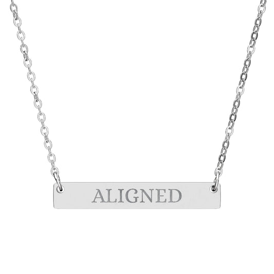 Silver bar necklace with engraved uppercase text "ALIGNED" on a sleek matte silver pendant, suspended on a delicate matching silver chain. Minimalist motivational affirmation jewelry for alignment, balance, and spiritual harmony.