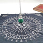 Silver pendulum with a polished green malachite sphere hanging over the center of a black spirit board cloth. The board features letters A-Z, numbers 0-9, "YES" and "NO", and a central Star of David symbol. Divination and dowsing tool setup.