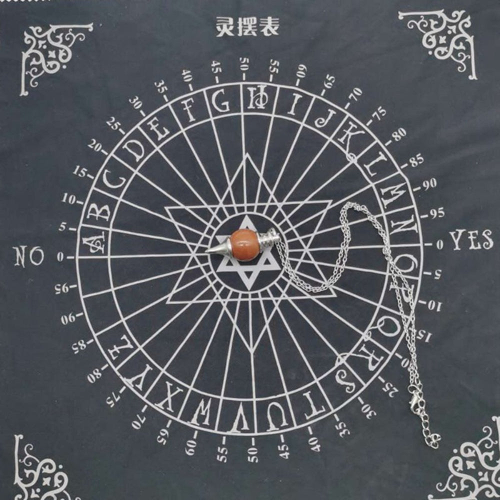 Spirit board divination chart (灵摆表) with a silver pendulum featuring a polished orange-red stone resting in the center. The circular wheel displays letters A-Z, numbers 0-9, "YES" and "NO", and a Star of David symbol, framed with ornate white corner decorations on a black background. Divination and dowsing tool.