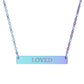 Iridescent bar necklace with engraved uppercase text "LOVED" on a gradient light blue to purple pendant, suspended on a matching rainbow-tinted chain. Minimalist motivational affirmation jewelry for self-love, worthiness, and emotional healing.