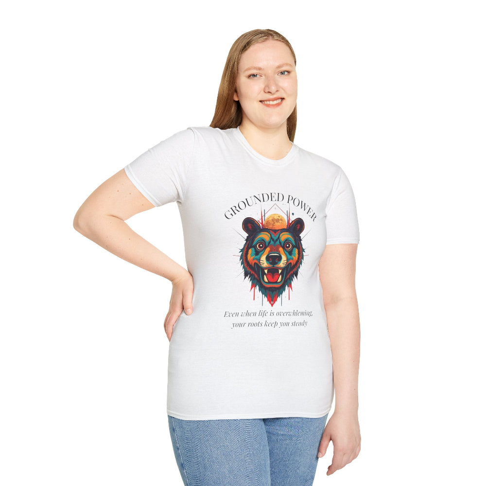 White plus-size unisex cotton t-shirt modeled by smiling woman with long blonde hair, hand on hip, featuring bold "Grounded Power" graphic on chest: vibrant abstract bear head portrait with intense expression, colorful geometric accents, and dynamic paint splatters in red, orange, teal, blue, and gold tones around an orange moon. Arched white text "GROUNDED POWER" above and smaller quote "Even when life is overwhelming, your roots keep you steady" below. Motivational spiritual empowerment crewneck tee.