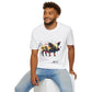 White unisex cotton t-shirt modeled by smiling man with curly hair and beard, seated pose, featuring bold Year of the Pig zodiac graphic: vibrant abstract pig portrait with detailed snout, ears, playful fierce expression, geometric accents, and dynamic multicolored paint splatters in gold, red, black, blue, teal, and orange tones exploding outward. Chinese text "猪年" (Year of the Pig) printed below in black. Chinese New Year zodiac motivational crewneck tee.