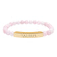 Bracelet with polished rose quartz beads in soft pink tones, natural translucent glow, paired with a gold-plated curved bar engraved "TAURUS" in uppercase letters. Stretch-fit zodiac-inspired crystal jewelry.