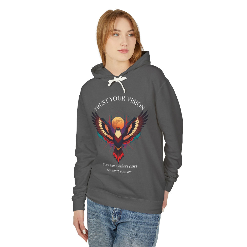Young woman modeling charcoal gray hoodie with colorful abstract eagle/phoenix graphic, "TRUST YOUR VISION" arched above, and inspirational quote "Even when others can't see what you see" below, relaxed front-facing pose